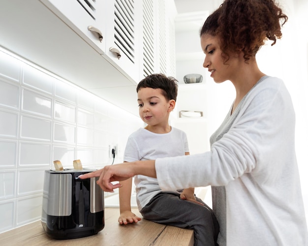 Foto grátis jovem mãe preparando um brinde com seu filho