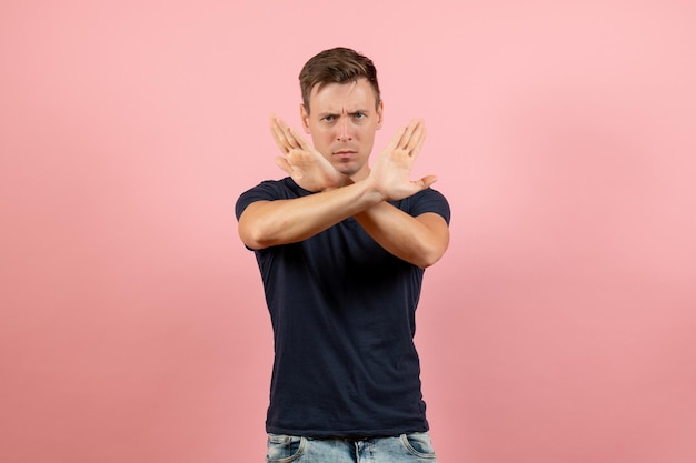 Jovem masculino com camisa azul escura, vista frontal, sinal de proibição em fundo rosa