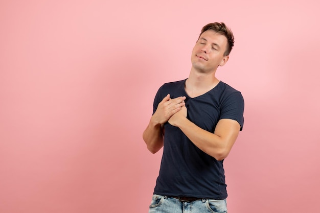 Foto grátis jovem masculino com camiseta azul-escura posando em fundo rosa