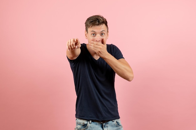 Jovem masculino com camiseta azul-escura posando em fundo rosa