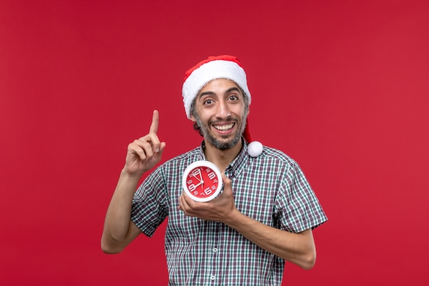 Jovem masculino com relógios redondos em fundo vermelho