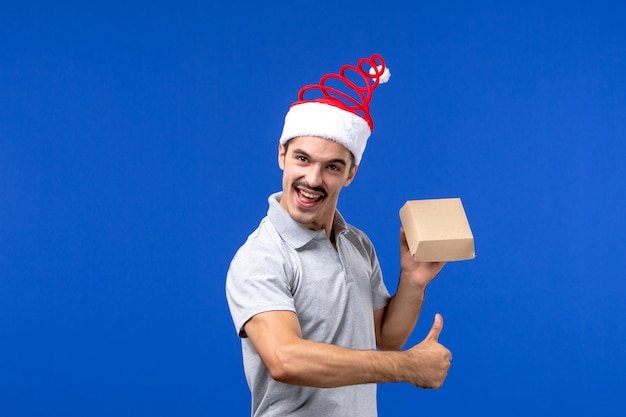 Jovem masculino segurando um pacote de comida na parede azul-claro do serviço de alimentação masculino