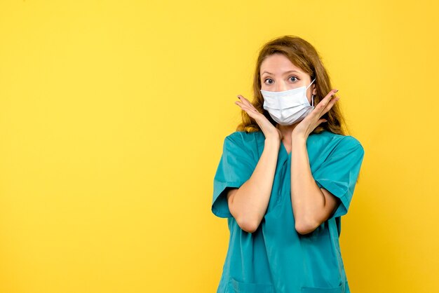 Foto grátis jovem médica com máscara no espaço amarelo de frente