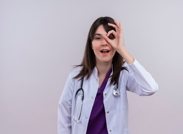 Jovem médica confiante em túnica médica e estetoscópio parece gesto em fundo branco isolado com espaço de cópia
