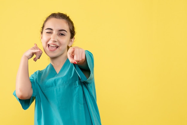 Jovem médica de frente para o terno médico em fundo amarelo