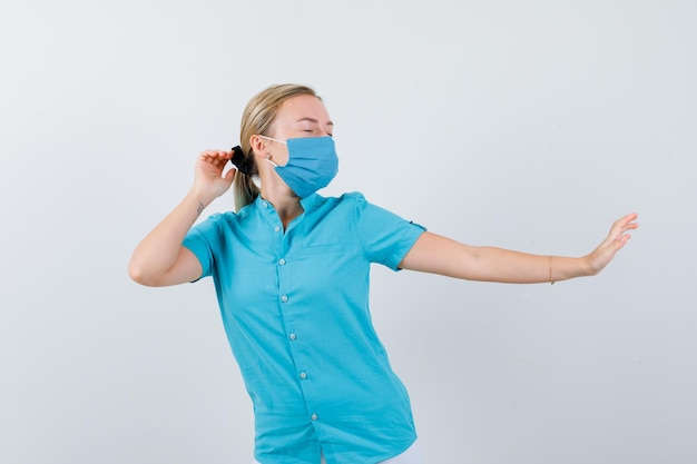 Jovem médica de uniforme mostrando gesto de pare e parecendo animada