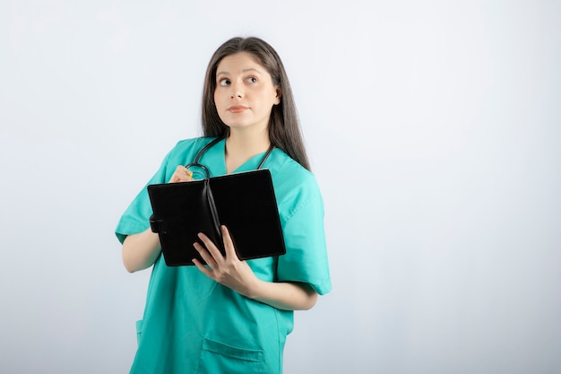 jovem médica em pé com o caderno e o lápis.