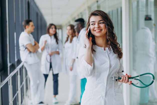 Jovem médica falando por telefone no corredor do hospital