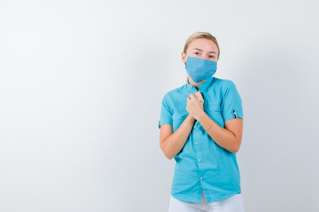 Jovem médica mostrando as mãos postas em um gesto de súplica em uniforme médico