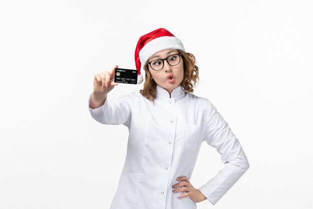 Jovem médica segurando um cartão de banco no chão branco, feriado, enfermeira, vista frontal, ano novo