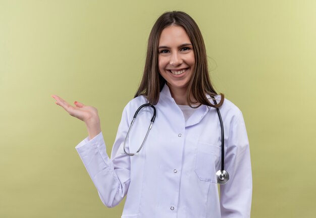 Jovem médica usando uma bata médica de estetoscópio - na parede verde