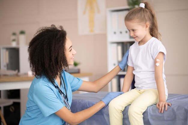 Jovem médico certificando-se de que a menina está bem após a vacinação