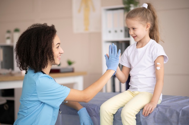 Jovem médico certificando-se de que a menina está bem após a vacinação