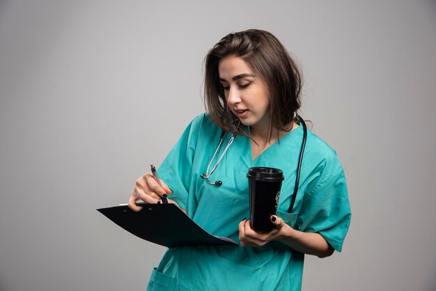 Jovem médico chechking notas sobre a doença em fundo cinza. foto de alta qualidade