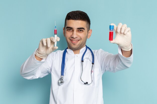 Jovem médico de terno branco com estetoscópio azul segurando a injeção com homem sorridente