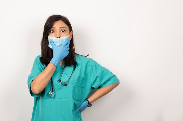 Jovem médico em máscara médica e luvas posando em fundo branco. Foto de alta qualidade