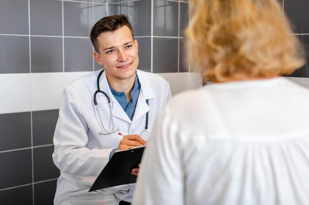 Jovem médico falando com um paciente no gabinete