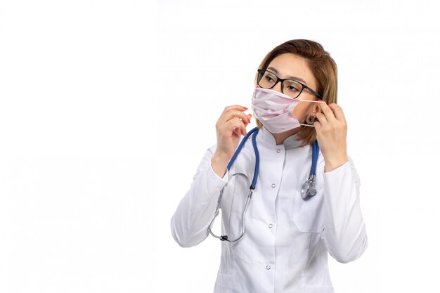 jovem médico feminino em traje médico branco usando máscara protetora branca em branco