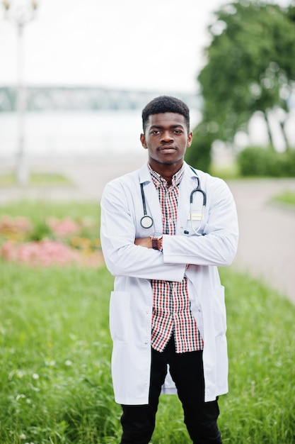 Jovem médico masculino americano africano no jaleco branco com um estetoscópio posou ao ar livre