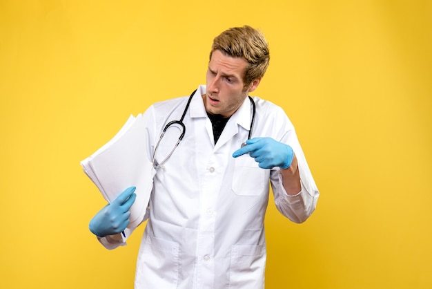 Jovem médico masculino, de frente, segurando análises sobre vírus humano de saúde médico de piso amarelo
