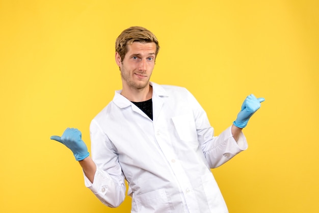 Jovem médico masculino sobre fundo amarelo pandemia médica covida