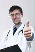 Foto grátis jovem médico sorridente com polegares para cima