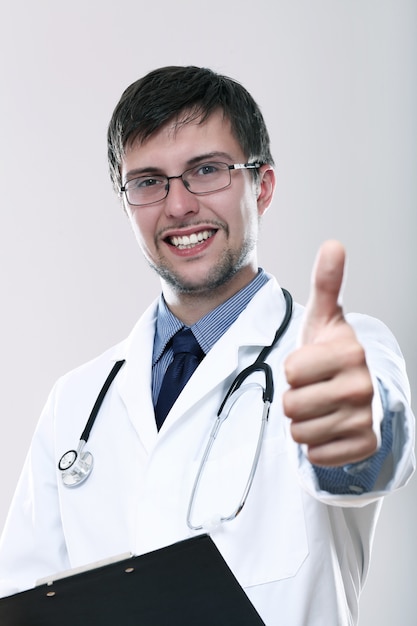 Jovem médico sorridente com polegares para cima