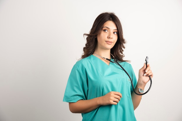 Jovem médico usando estetoscópio em branco.