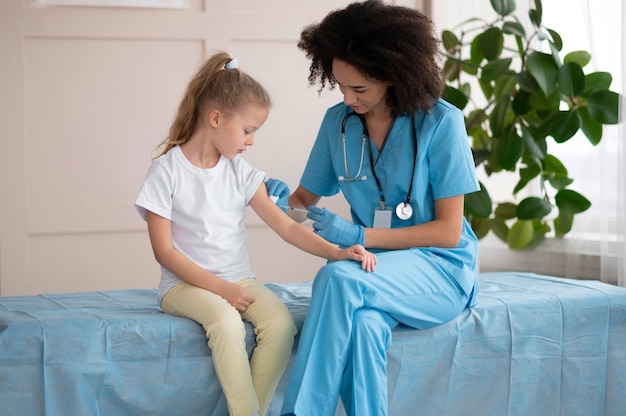 Jovem médico vacinando uma menina