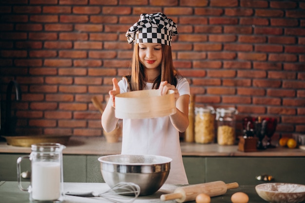 Jovem menina assando bolos na cozinha no café da manhã