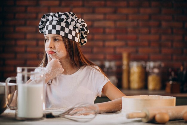 Jovem menina assando bolos na cozinha no café da manhã