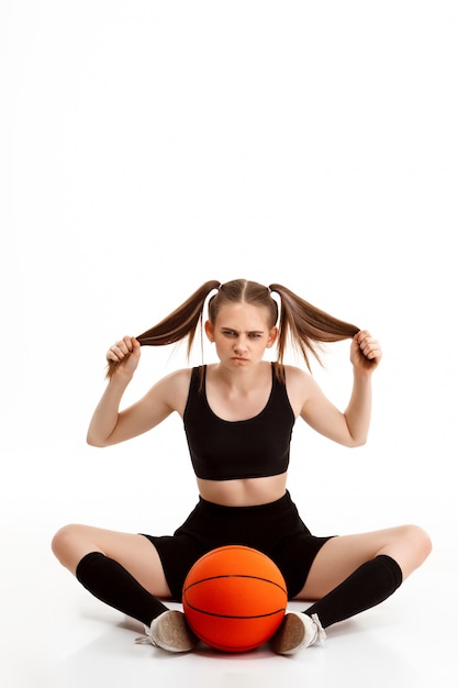 Foto grátis jovem menina bonita posando com basquete sobre parede branca