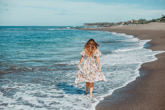 jovem menina linda posando na praia, oceano, ondas, sol brilhante e pele bronzeada