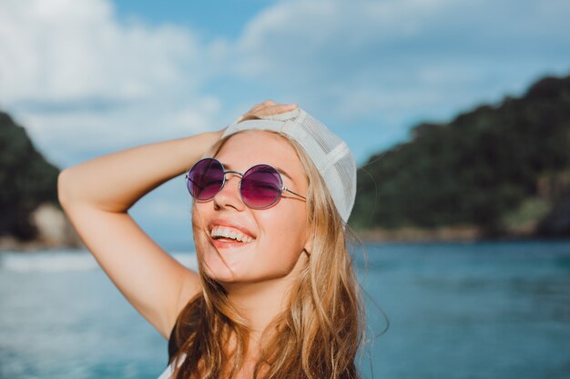 jovem menina linda posando na praia, oceano, ondas, sol brilhante e pele bronzeada