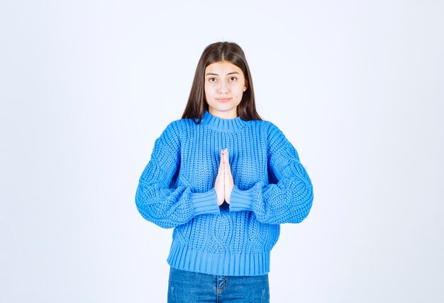 Jovem menina morena com camisola azul em pé branco.