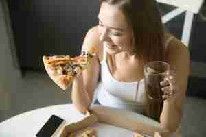 Foto grátis jovem, menina sorridente com uma fatia de pizza