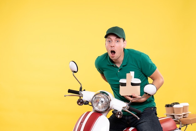 Foto grátis jovem mensageiro de frente para o homem de uniforme verde com café em amarelo