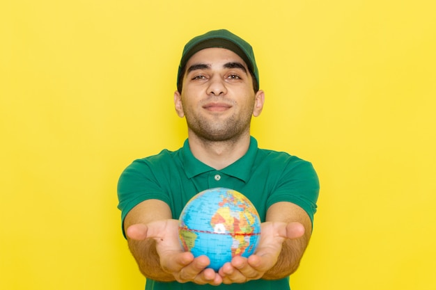 Jovem mensageiro masculino com boné verde e camisa verde segurando o globo amarelo