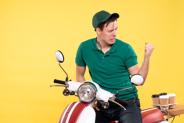 Jovem mensageiro masculino com uniforme verde na bicicleta amarela