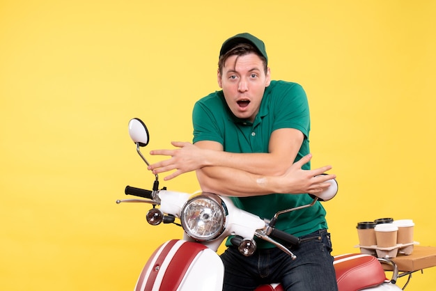 Jovem mensageiro masculino com uniforme verde na bicicleta amarela