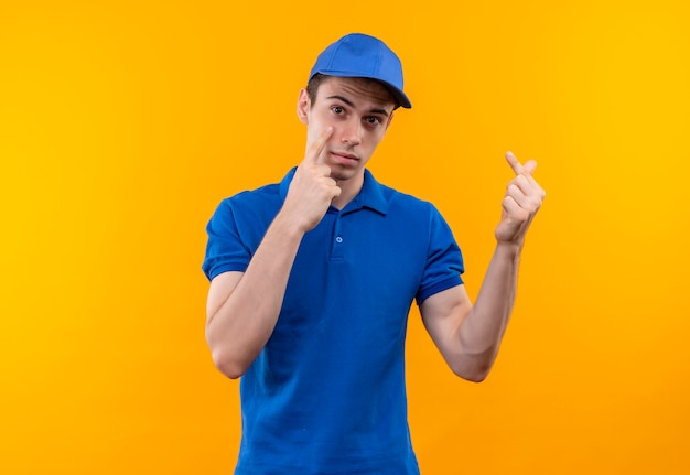 Jovem mensageiro vestindo uniforme azul e boné azul fazendo cara de infeliz e mostra dinheiro com os dedos