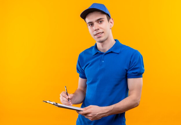 Jovem mensageiro vestindo uniforme e boné azuis segurando uma prancheta e um lápis