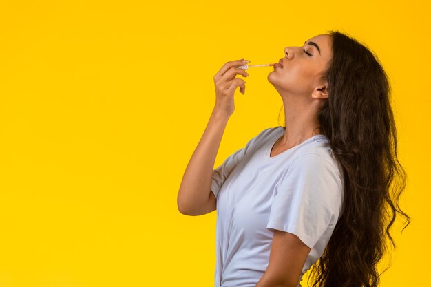 Jovem modelo aplicando brilho labial e colocando a cabeça para cima.