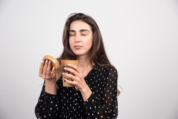 Jovem modelo cheirando uma xícara de café