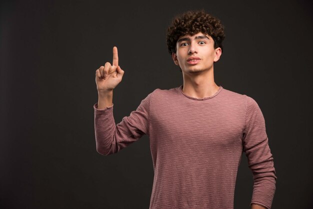 Jovem modelo com cabelos cacheados, fazendo perguntas.