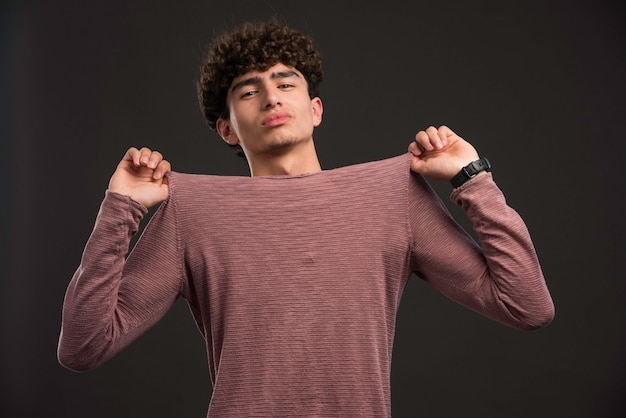 Jovem modelo com cabelos cacheados, segurando sua camisa.