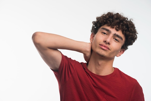 Jovem modelo com cabelos cacheados tocando seu pescoço.