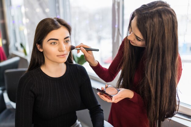 Jovem modelo com grandes olhos verdes está tendo o procedimento de maquiagem