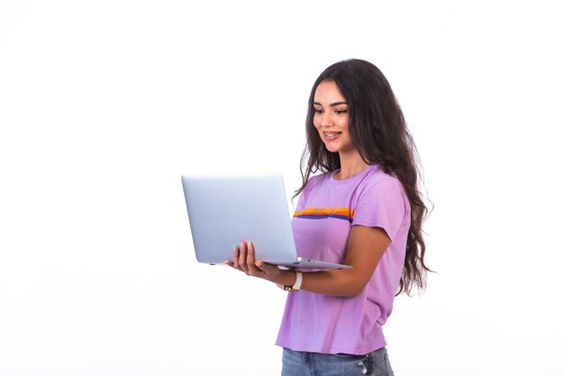 Jovem modelo segurando um laptop prateado e fazendo videochamada