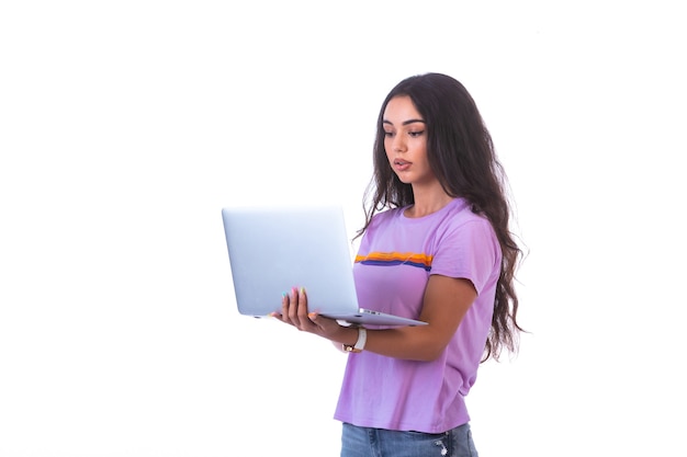 Jovem modelo segurando um laptop prateado e fazendo videochamada